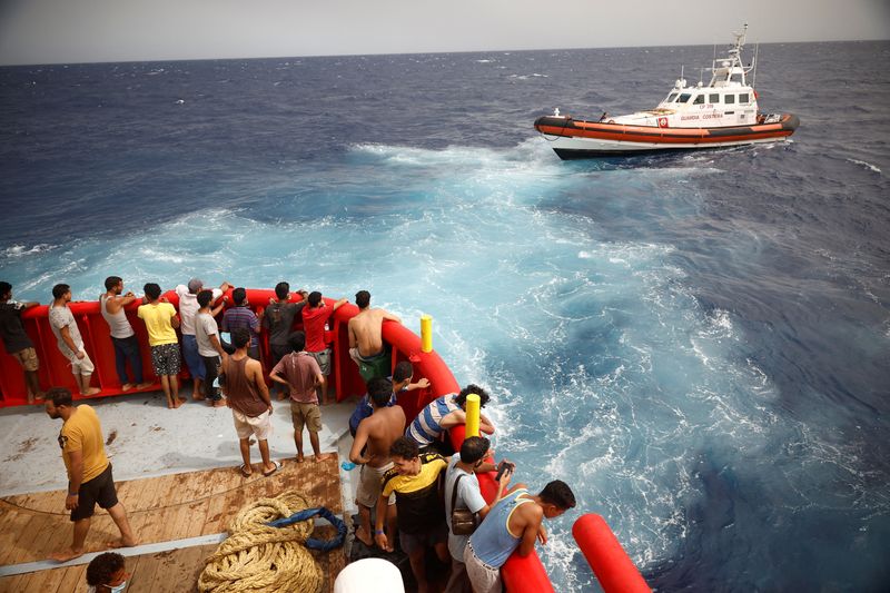 &copy; Reuters. Migranti a bordo dell'imbarcazione di salvataggio dell'ONG Proactiva Open Arms Uno guardano la nave Guardia Costiera diretta verso l'isola di Lampedusa, nel Mediterraneo centrale, vicino all'isola di Lampedusa, Italia, 19 agosto 2022. REUTERS/Juan Medina/