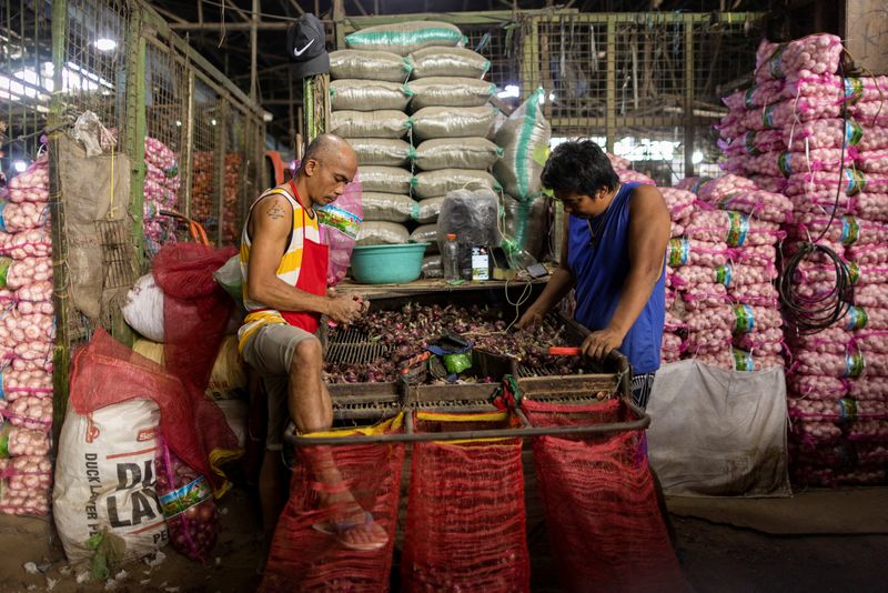 &copy; Reuters. FILE PHOTO-Workers remove roots from onions before they are sold at a public market in Quezon City, Metro Manila, Philippines, February 9, 2023. REUTERS/Eloisa Lopez/File Photo