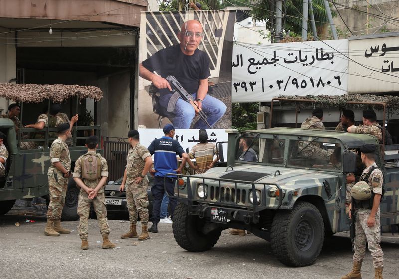© Reuters. عناصر من الجيش اللبناني يقفون يوم الأربعاء بالقرب من ملصق  لمواطن من السكان المحليين يدعى فادي بجاني قتل خلال اشتباكات وقعت في قرية الكحالة . تصوير : محمد عزاقير - رويترز .  