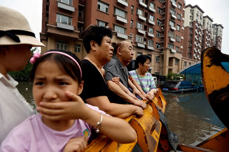 &copy; Reuters. Pessoas em um carregador durante remoção em um complexo residencial inundado após as chuvas e inundações trazidas pelos remanescentes do tufão Doksuri, em Zhuozhou, província de Hebei, China
03/08/2023
REUTERS/Tingshu Wang