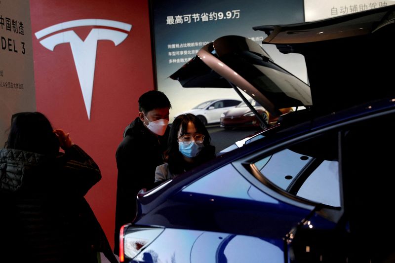 © Reuters. FILE PHOTO: Visitors wearing face masks check a China-made Tesla Model Y sport utility vehicle (SUV) at the electric vehicle maker's showroom in Beijing, China January 5, 2021. REUTERS/Tingshu Wang//File Photo