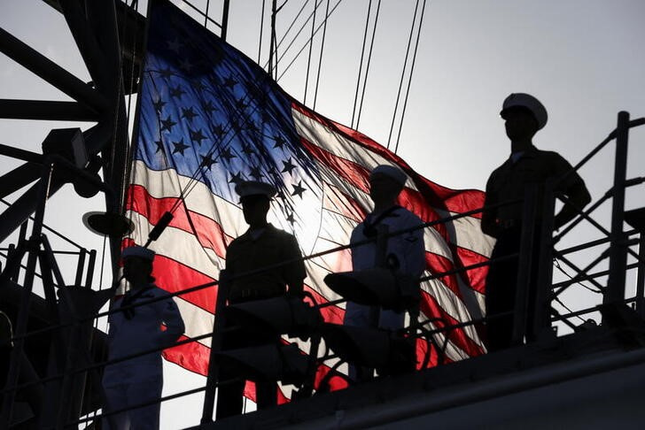 © Reuters. A U.S. flag flutters in the background as members of the U.S. Marines and the U.S. Navy stand on a deck of the USS Bataan, a U.S. Navy Wasp-class amphibious assault ship, as it takes part in a parade of ships during Fleet Week 2022 in New York, U.S. May 25, 2022. REUTERS/Andrew Kelly