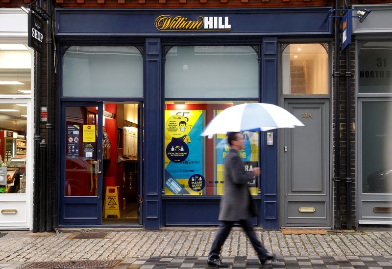 © Reuters. FILE PHOTO: A man walks past a branch of bookmaker William Hill in central London, Britain October 21, 2020. REUTERS/John Sibley/File Photo