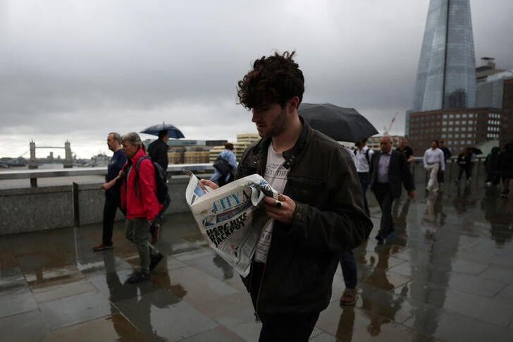 © Reuters. A commuter reads a City A.M. newspaper while crossing London Bridge in London, Britain August 2, 2023. REUTERS/Hollie Adams