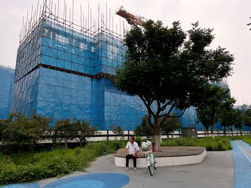 &copy; Reuters. FOTO DE ARCHIVO: Una persona sentada cerca de una obra de construcción de edificios residenciales del promotor chino Country Garden, en Pekín, China. 11 de agosto de 2023. REUTERS/Tingshu Wang