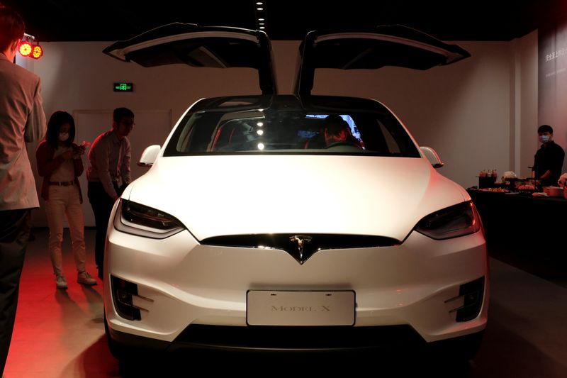 &copy; Reuters. FILE PHOTO: People wearing face masks following the coronavirus disease (COVID-19) outbreak check a Tesla Model X sport utility vehicle at a new Tesla showroom in Shanghai, China May 8, 2020. REUTERS/Yilei Sun/File Photo