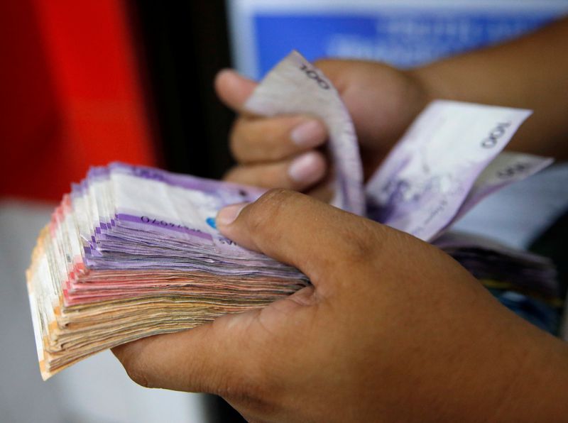 &copy; Reuters. FILE PHOTO: A man counts a wad of Philippine Peso bills he received from a relative working abroad at a money remittance center in Makati City, Metro Manila, Philippines September 19, 2018. REUTERS/Eloisa Lopez/File Photo