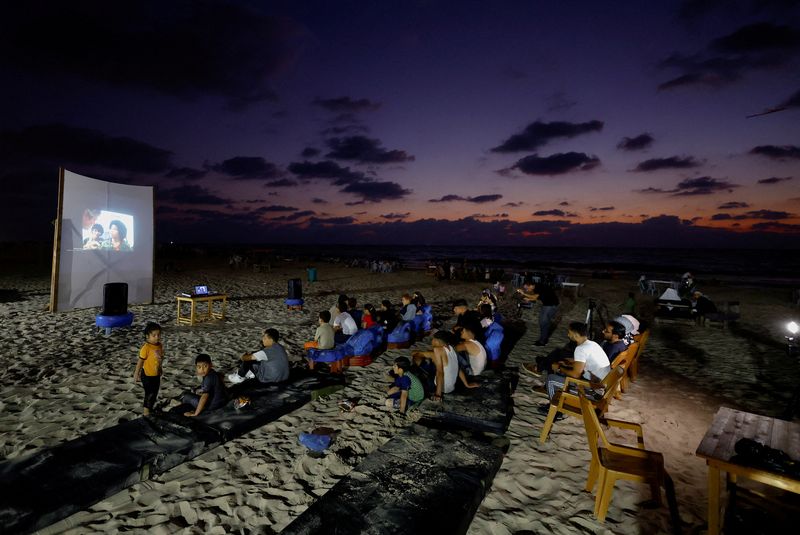 &copy; Reuters. عائلات فلسطينية تشاهد شاشة عرض كبيرة في مقهى على شاطئ البحر خلال حدث سينمائي نادر في مدينة غزة يوم 11 أغسطس آب 2023. تصوير: محمد سالم - رويترز.