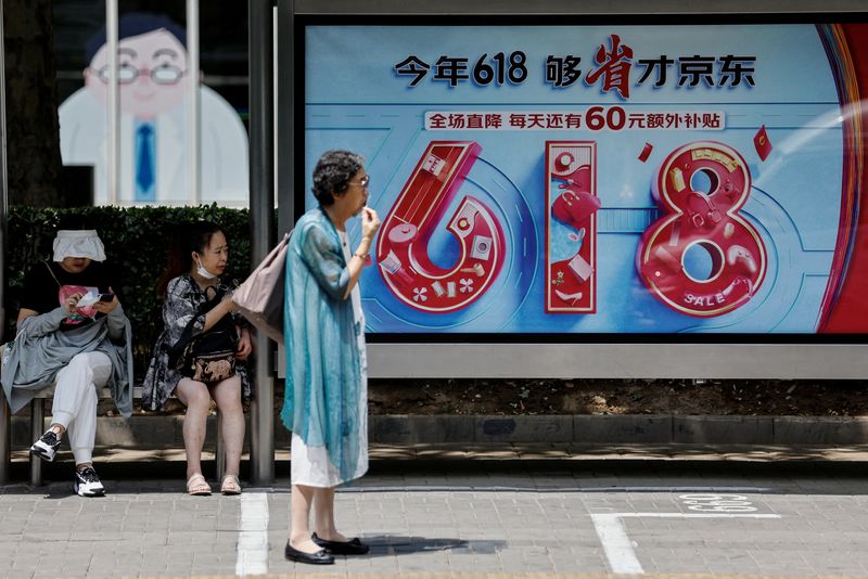 &copy; Reuters. Des personnes attendent un bus près d'un panneau publicitaire de JD.com pour le festival du shopping "618", à Pékin, en Chine. /Photo prise le 12 juin 2023/REUTERS/Tingshu Wang/