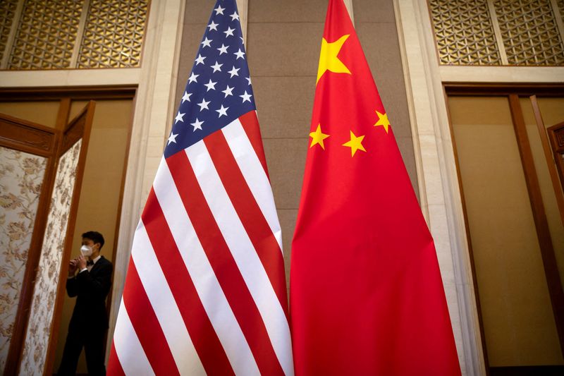 © Reuters. FILE PHOTO: A staff member wearing a face mask walks past United States and Chinese flags set up before a meeting between Treasury Secretary Janet Yellen and Chinese Vice Premier He Lifeng at the Diaoyutai State Guesthouse in Beijing, China, Saturday, July 8, 2023. Mark Schiefelbein/Pool via REUTERS/File Photo