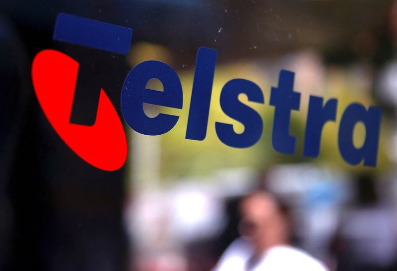 &copy; Reuters. FILE PHOTO: A pedestrian walks past a Telstra logo adorning a phone booth in the central business district (CBD) of Sydney in Australia, February 13, 2018. REUTERS/David Gray/File Photo