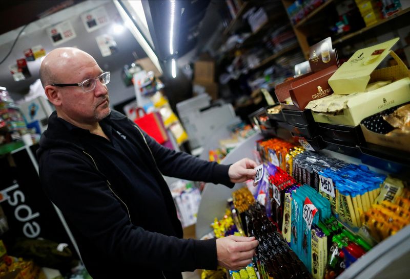 &copy; Reuters. Convenience store owner Ernesto Acuna, 50, raises the price on the tags of chocolate bars in his store after the government devalued the peso, following Argentina's primary elections, in Buenos Aires, Argentina August 17, 2023. REUTERS/Agustin Marcarian