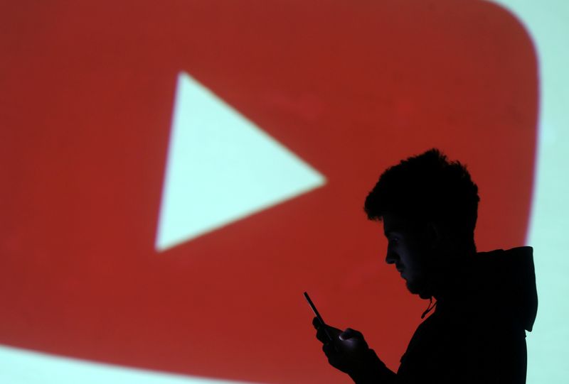 &copy; Reuters. FILE PHOTO: A silhouette of a mobile user is seen next to a screen projection of Youtube logo in this picture illustration taken March 28, 2018.  REUTERS/Dado Ruvic/Illustration