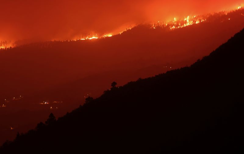 &copy; Reuters. مشهد يُظهر حريقا فوق الجبال بالقرب من منازل خالية في إحدى قرى جزيرة تينيريفي بإسبانيا يوم الأحد. تصوير: ناشو دوسي - رويترز.