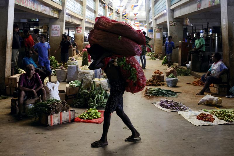 &copy; Reuters. FILE PHOTO: A worker carries a sack of vegetables at the whole sale market, as Sri Lanka's key inflation rate eases to 25.2% in May, at a stall at a main market in Colombo, Sri Lanka June 1, 2023. REUTERS/Dinuka Liyanawatte/File Photo