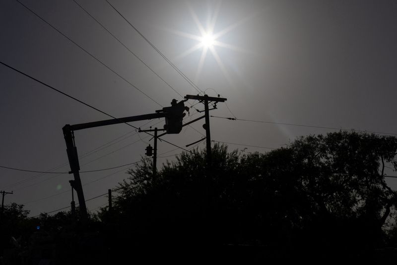 &copy; Reuters. 　８月２２日、米中西部では今週、記録的な電力需要増加で電力システムに打撃が及んでいる。写真は送電ケーブルを修理する作業員。７月２８日、テキサス州で撮影（２０２３年　ロイタ