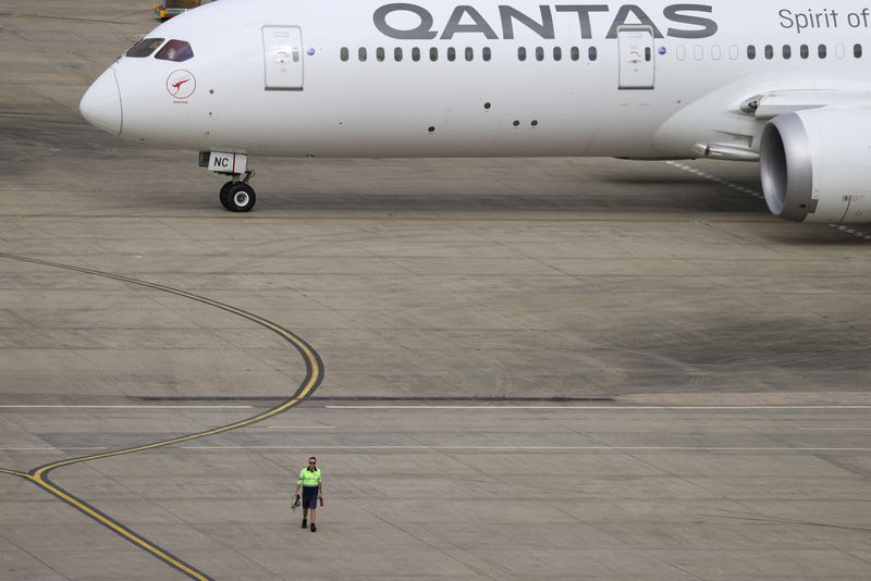 &copy; Reuters. Photo d'archives d'un employé qui marche près d'un avion Qantas à l'aéroport de Sydney, en Australie. /Photo prise le 29 novembre 2021 à Sydney, Australie/REUTERS/Loren Elliott