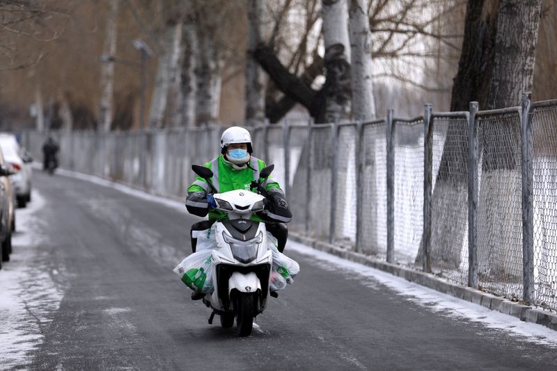 &copy; Reuters. FILE PHOTO: A Meituan delivery worker rides a scooter carrying vegetables on a snowy day in Beijing, China January 19, 2021. REUTERS/Tingshu Wang/File Photo