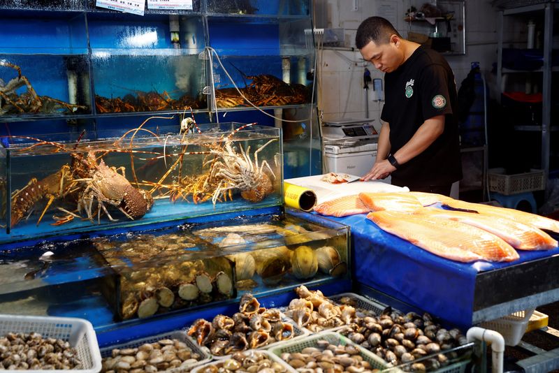 &copy; Reuters. A vendor processes surf clams at a fish and seafood stall, at a seafood market in Beijing, China August 24, 2023. REUTERS/Florence Lo