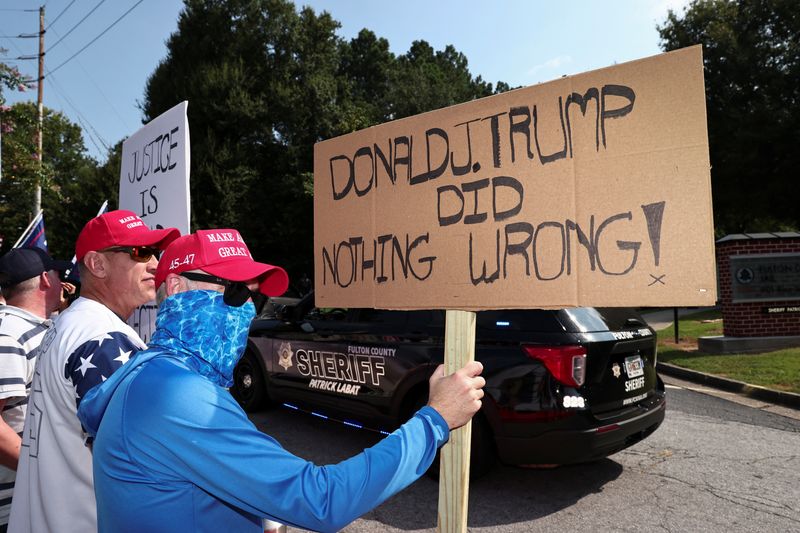 © Reuters. Apoiador de Donald Trump segura cartaz que afirma que o  ex-presidente dos EUA não fez nada de errado, na entrada da prisão do Condado de Fulton, na Geórgia
24/08/2023
REUTERS/Dustin Chambers