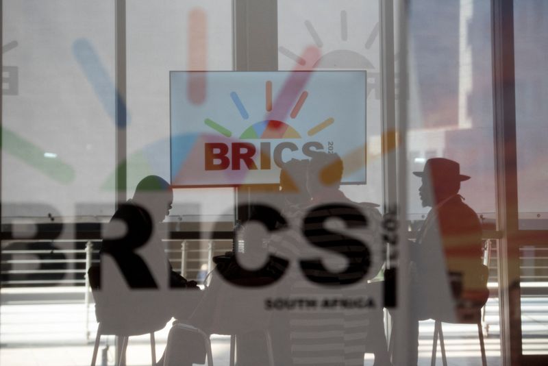 &copy; Reuters. أشخاص يجلسون خلال زجاج عليه شعار بريكس في أثناء قمة بريكس في جوهانسبرج يوم الثلاثاء. تصوير: أليت بريتوريوس - رويترز.