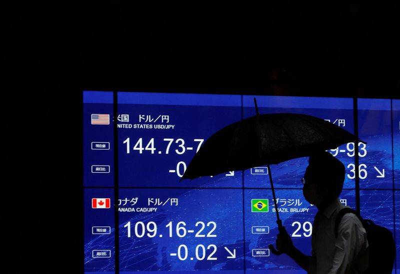 &copy; Reuters. Un uomo passa davanti a un monitor elettrico che mostra il tasso di cambio dello yen giapponese rispetto al dollaro statunitense e ad altre valute estere a Tokyo, Giappone, 30 giugno 2023. REUTERS/Issei Kato