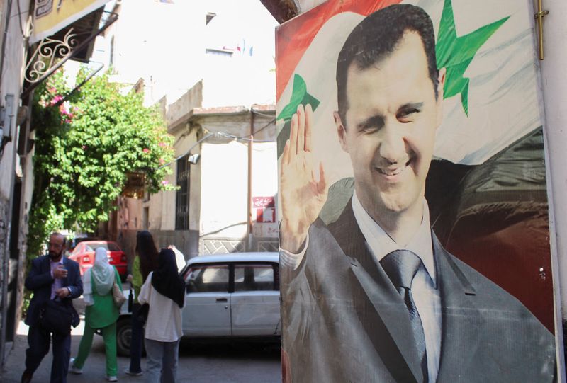 &copy; Reuters. FILE PHOTO: People walk near a poster depicting Syria's President Bashar al-Assad in Damascus, Syria May 19, 2023. REUTERS/Firas Makdesi