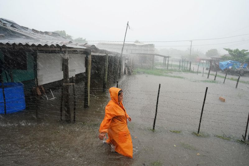 © Reuters. A woman walks on a flooded street as Storm Idalia makes landfall in Cuba, Guanimar, Cuba, August 28, 2023.  REUTERS/Alexandre Meneghini