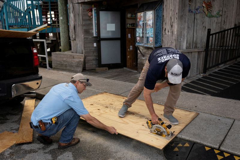 &copy; Reuters. FILE PHOTO: Men cut plywood in front of a store ahead of the arrival of Hurricane Idalia in Cedar Key, Florida, U.S., August 29, 2023. REUTERS/Marco Bello/File Photo