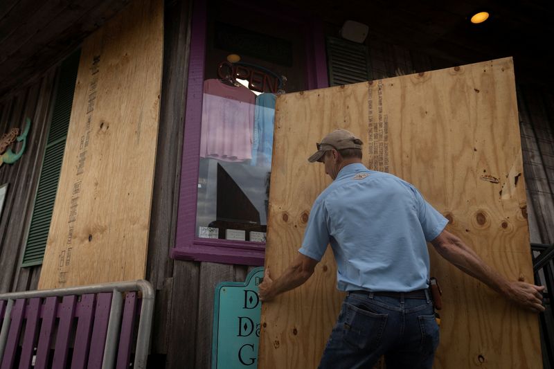 © Reuters. A man places plywood in front of a store ahead of the arrival of Hurricane Idalia in Cedar Key, Florida, U.S., August 29, 2023. REUTERS/Marco Bello