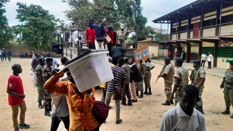 © Reuters. Des agents électoraux portent des urnes alors que des personnes attendent l'ouverture d'un bureau de vote lors de l'élection présidentielle à Libreville, au Gabon. /Photo prise le 26 août 2023/REUTERS/Gerauds Wilfried Obangome