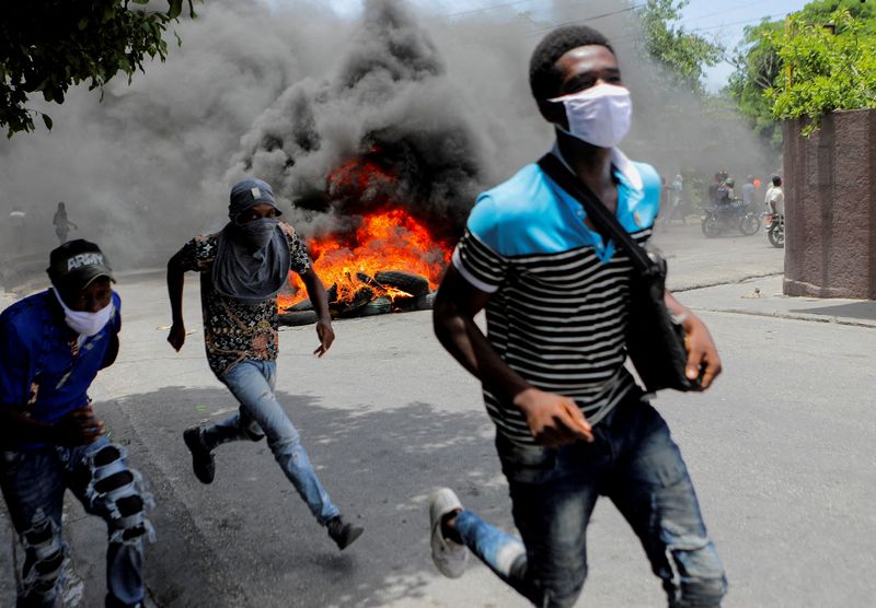 &copy; Reuters. رجال يركضون بجوار إطارات محترقة أثناء احتجاج يطالب بإنهاء عنف العصابات في بورت او برنس في هايتي يوم 14 أغسطس آب 2023. تصوير: رالف تيدي إيرول - رو