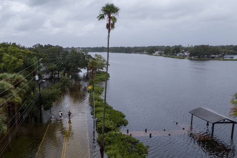 © Reuters. Residents walk down a flooded street in the aftermath of Hurricane Idalia in Tarpon Springs, Florida, U.S., August 30, 2023. REUTERS/Adrees Latif