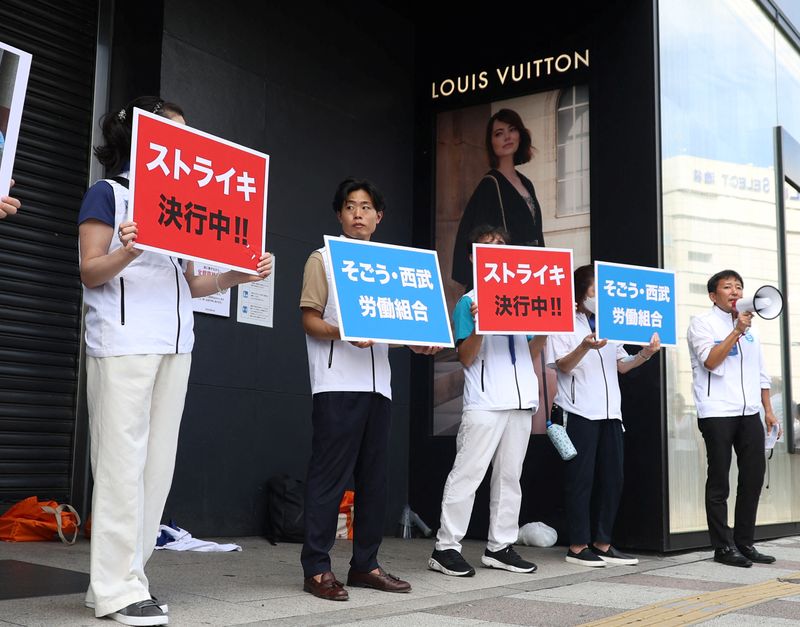 © Reuters. Union workers of Sogo & Seibu hold banners which read 'on strike' in front of the company's flagship Seibu Ikebukuro store in Tokyo, Japan August 31, 2023. REUTERS/Irene Wang