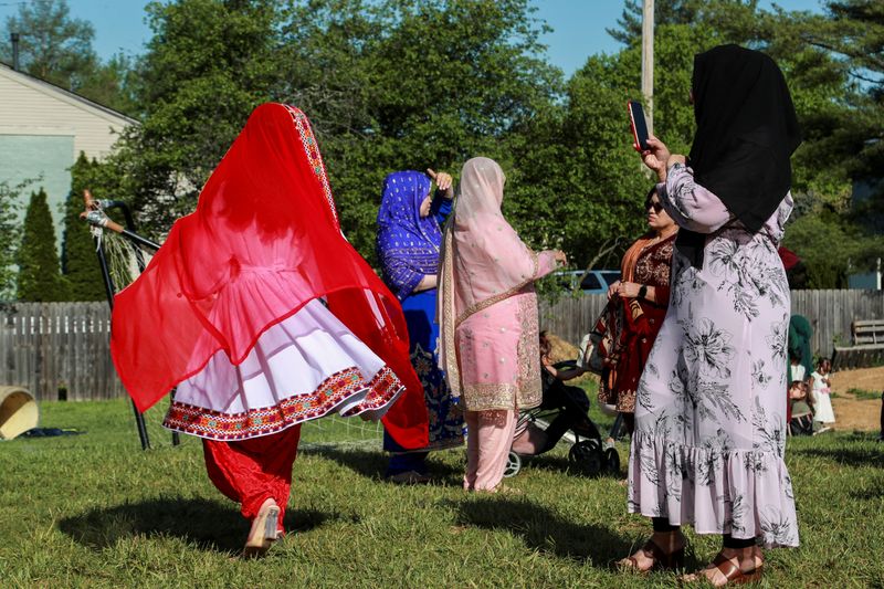 © Reuters. FILE PHOTO: An Afghan refugee takes a photo of her friend in her traditional clothes while celebrating the Muslim festival at the Guiding Light Islamic Center in Louisville, Kentucky, U.S., May 2, 2022.  REUTERS/Amira Karaoud/File Photo
