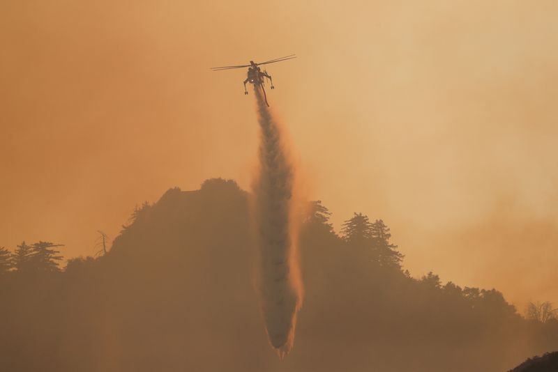 © Reuters. FILE PHOTO: A helicopter makes a water drop over the Bobcat Fire burning near Mount Wilson in the Angeles National Forest, near Los Angeles, U.S., September 23, 2020. REUTERS/Mario Anzuoni/File Photo