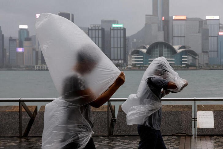 &copy; Reuters. Varias personas caminan protegidas con plásticos durante el embate del supertifón Saola en Hong Kong. 1 septiembre 2023. REUTERS/Tyrone Siu