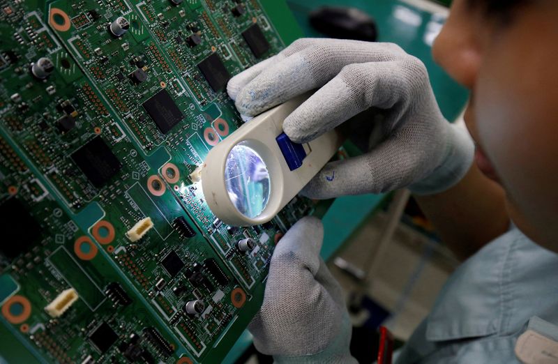 &copy; Reuters. FILE PHOTO: A woman looks through a magnifying glass to check errors of a printer circuit board at Manutronics Factory in Bac Ninh province, Vietnam May 30, 2018. REUTERS/Kham/File Photo