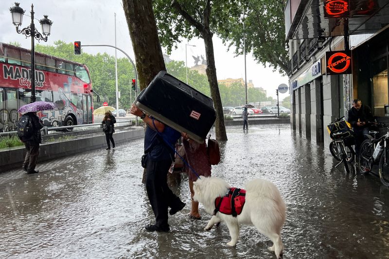&copy; Reuters. شخصان يحتميان من هطول الأمطار الغزيرة في العاصمة الإسبانية مدريد في 28 مايو أيار 2023 . تصوير : ناتشو دوس - رويترز . 