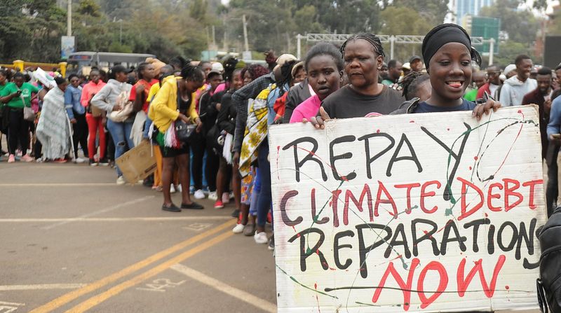 © Reuters. A member of the civil society holds a placard as others queue during a peaceful protest against the continent's inaugural climate summit, marching against the use of fossil fuels in the region while demanding that governments and industries transition to renewable energy in Nairobi, Kenya September 4, 2023. REUTERS/John Muchucha
