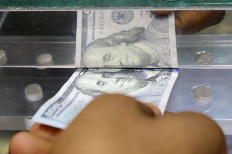 &copy; Reuters. A man inserts a U.S. dollar banknote into the window of a local currency exchange in Aden, Yemen June 29, 2021. Picture taken June 29, 2021. REUTERS/Fawaz Salman