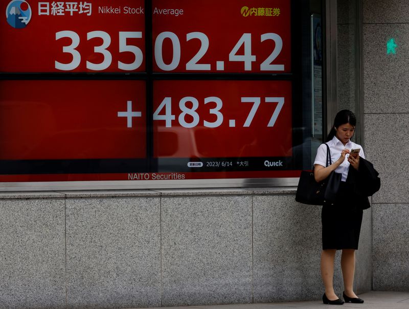 &copy; Reuters. سيدة تقف أمام لوحة إلكترونية تعرض حركة الأسهم على مؤشر نيكي الياباني في طوكيو يوم 14 يونيو حزيران 2023. تصوير: كيم كيونج هوون - رويترز.