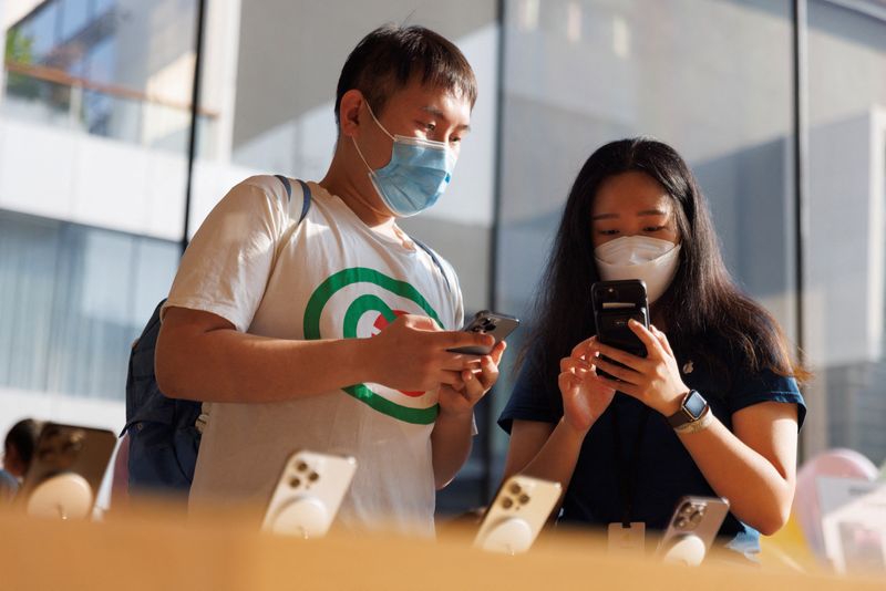 &copy; Reuters. Un client et une vendeuse regardant un iPhone dans un Apple Store à Pékin. /Photo prise le 16 septembre 2022/REUTERS/Thomas Peter