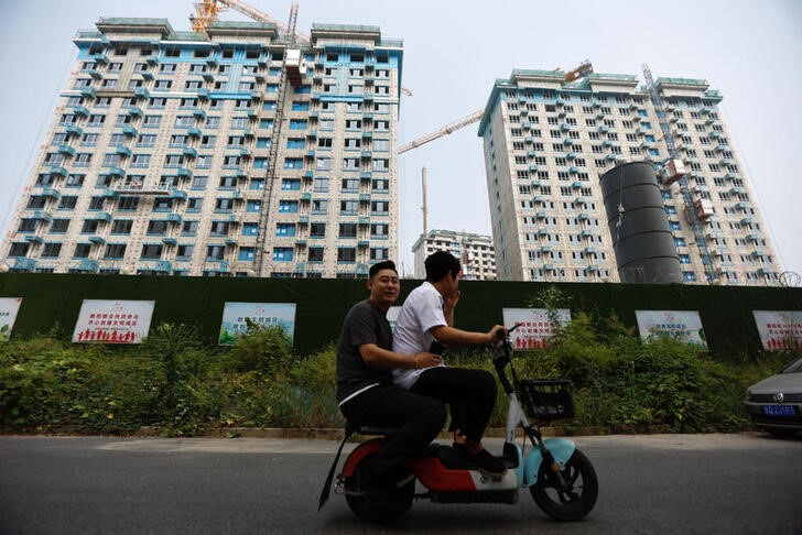 &copy; Reuters. Dos personas pasan en moto frente a edificios residenciales en construcción en Pekín, China. 6 septiembre 2023. REUTERS/Tingshu Wang