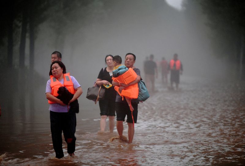 &copy; Reuters. أشخاص يعبرون مياه الفيضانات بعد هطول أمطار غزيرة في تشوتشو بمقاطعة خبي بالصين يوم الأول من أغسطس آب 2023. صورة لرويترز. 