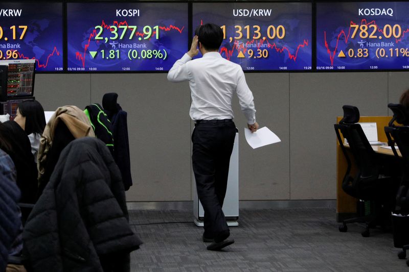 &copy; Reuters. FILE PHOTO: A currency dealer walks past electronic boards showing the Korean Composite Stock Price Index  (KOSPI) and the exchange rate between the U.S. dollar and South Korean won at a dealing room of a bank, in Seoul, South Korea, March 16, 2023. REUTE