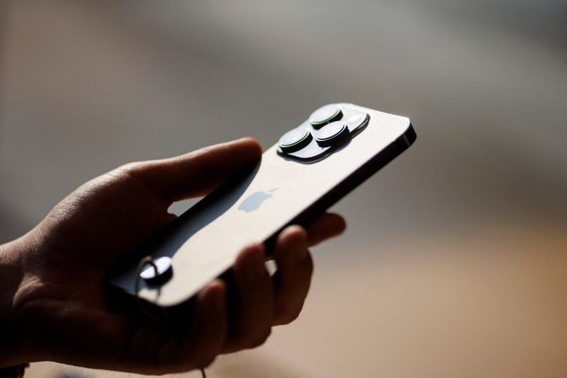 &copy; Reuters. FILE PHOTO: A man holds an iPhone 14 as Apple Inc's new models go on sale at an Apple store in Beijing, China, September 16, 2022. REUTERS/Thomas Peter/File Photo