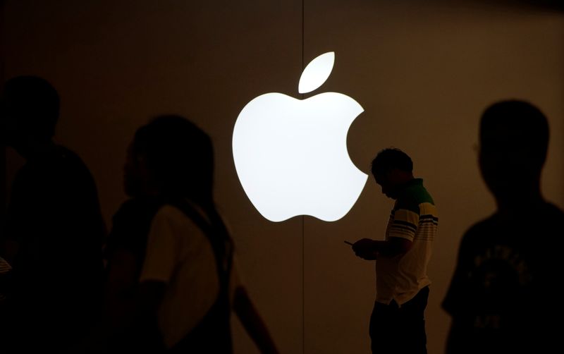 &copy; Reuters. FOTO DE ARCHIVO: Un hombre mira la pantalla de su teléfono móvil frente a un logotipo de Apple en el exterior de una tienda de esta marca en Shanghái (China) el 30 de julio de 2017. REUTERS/Aly Song/Foto de archivo