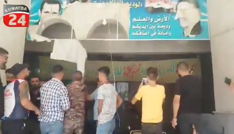 © Reuters. Protesters tear down a poster of Syria's President Bashar al-Assad from the facade of the Farmers' Union building in the southern Druze city of Sweida, Syria, September 8, 2023 in this screengrab taken from a handout video. Suwayda 24/Handout via REUTERS