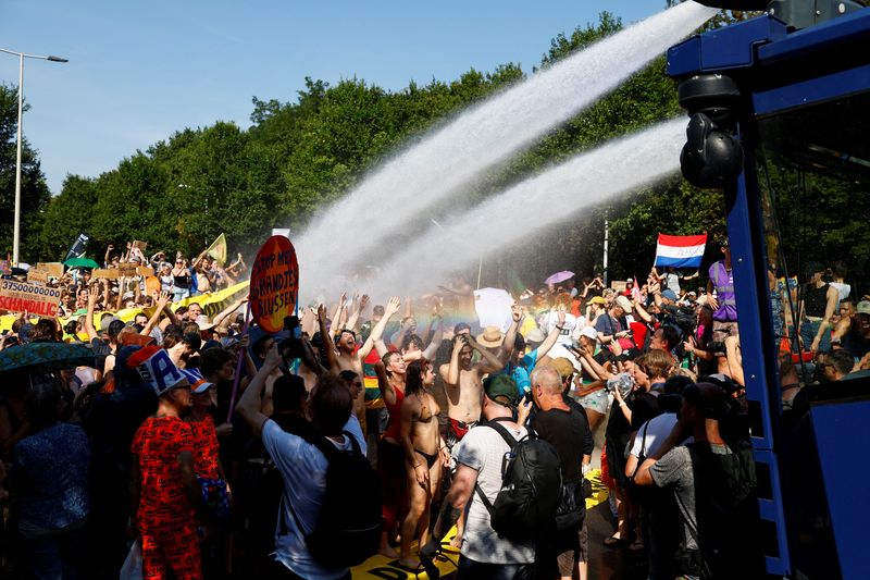© Reuters. People react to a water cannon, as climate activists block the A12 highway in The Hague, Netherlands, September 9, 2023. REUTERS/Piroschka van de Wouw